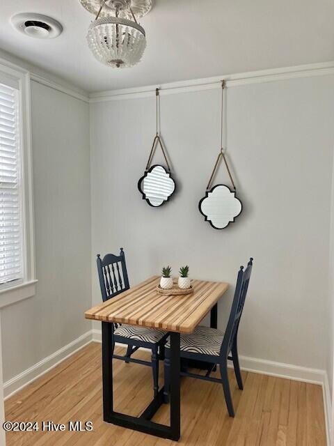 dining space with light hardwood / wood-style flooring, ornamental molding, and a notable chandelier