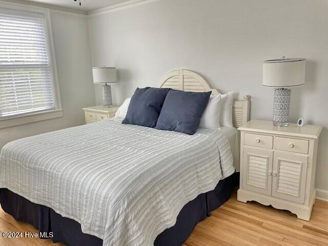 bedroom featuring light wood-type flooring and crown molding