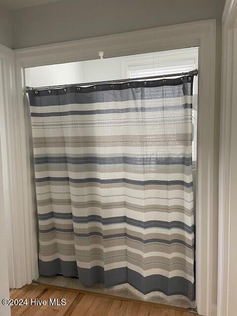 bathroom featuring a shower with shower curtain and hardwood / wood-style flooring