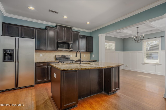 kitchen with pendant lighting, appliances with stainless steel finishes, beamed ceiling, an island with sink, and coffered ceiling