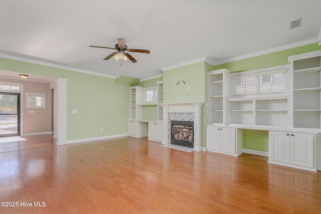 unfurnished living room featuring ceiling fan, light wood-type flooring, a tile fireplace, and ornamental molding