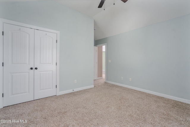 unfurnished bedroom featuring ceiling fan, a closet, light carpet, and vaulted ceiling