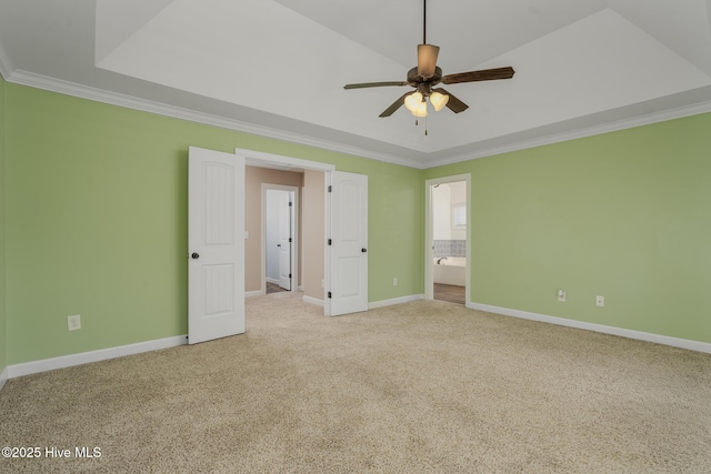 unfurnished bedroom with ceiling fan, ensuite bathroom, a tray ceiling, and ornamental molding