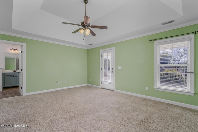 unfurnished room featuring ceiling fan, carpet, ornamental molding, and a tray ceiling