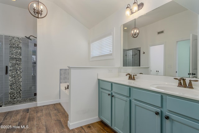 bathroom with plus walk in shower, an inviting chandelier, lofted ceiling, and vanity