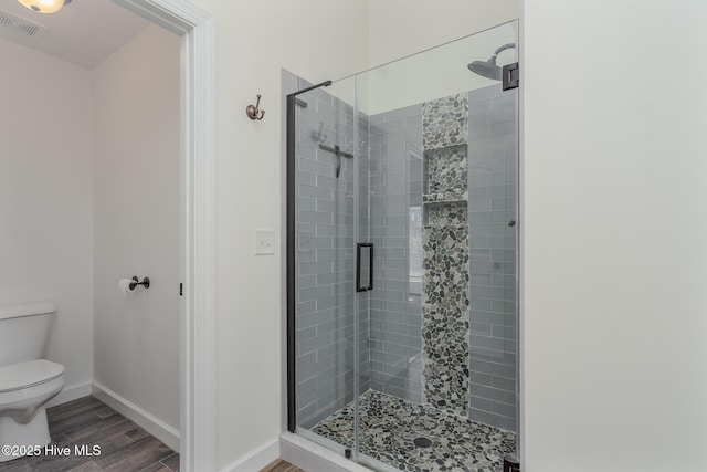 bathroom featuring toilet and a shower with door