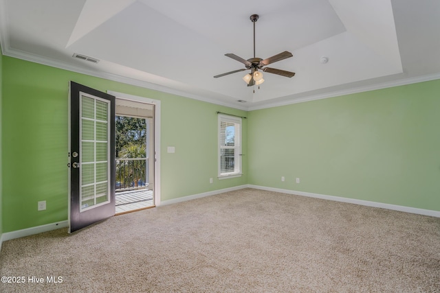 empty room with ceiling fan, a tray ceiling, ornamental molding, and carpet flooring