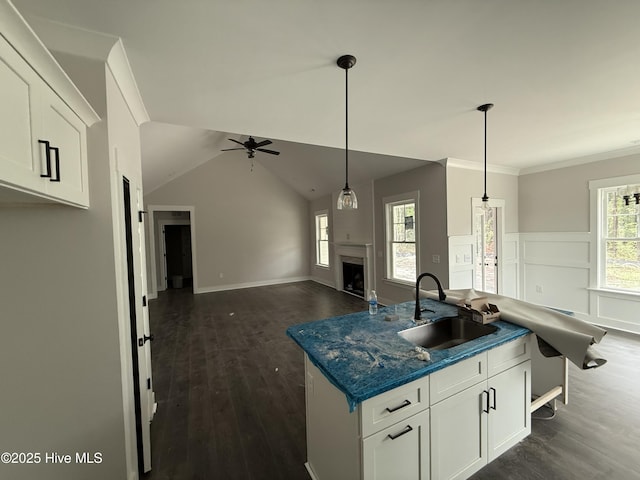 kitchen featuring a sink, ceiling fan, dark countertops, dark wood finished floors, and ornamental molding