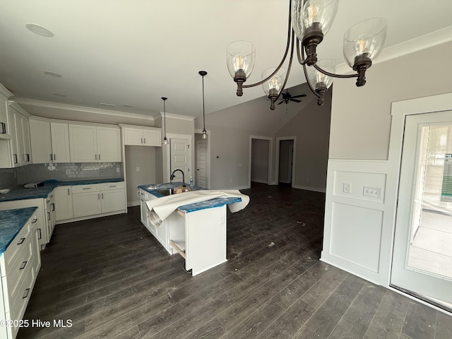 kitchen with a sink, a chandelier, white cabinets, tasteful backsplash, and dark countertops