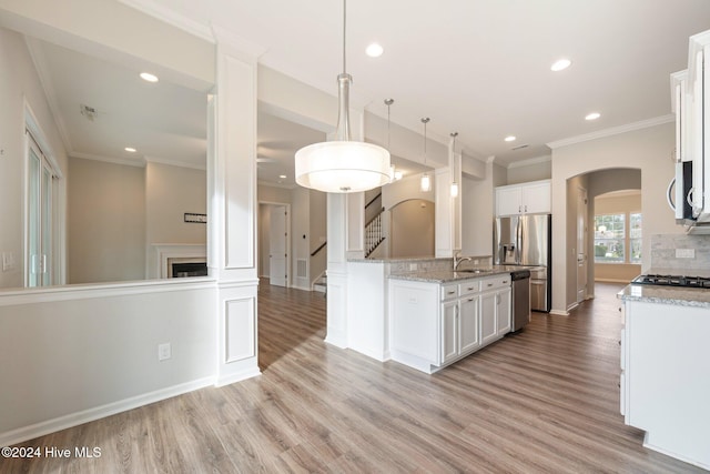 kitchen featuring white cabinetry, stainless steel appliances, light hardwood / wood-style flooring, backsplash, and pendant lighting