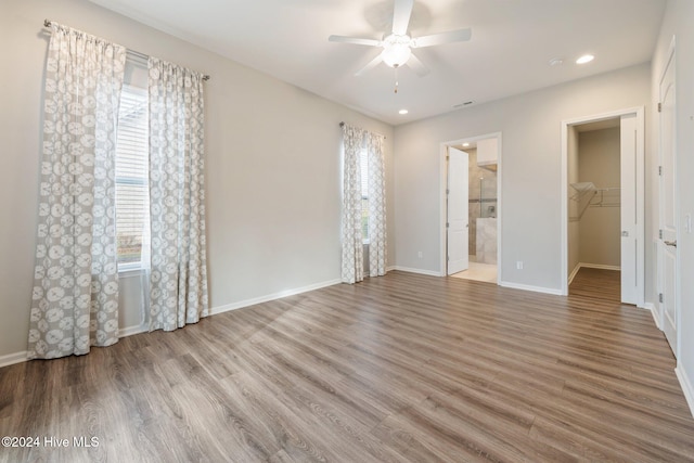 unfurnished bedroom with hardwood / wood-style floors, a walk in closet, and multiple windows