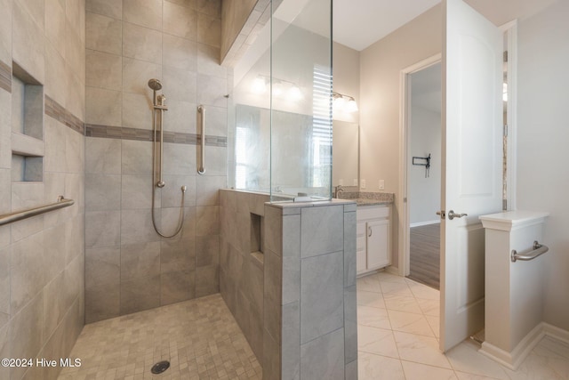 bathroom with a tile shower, tile patterned floors, and vanity