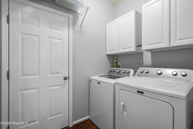 washroom with washing machine and dryer, dark hardwood / wood-style flooring, and cabinets