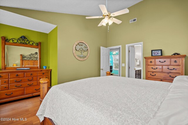 bedroom featuring connected bathroom, ceiling fan, light hardwood / wood-style flooring, and vaulted ceiling