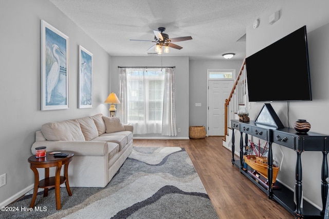 living room featuring ceiling fan, hardwood / wood-style floors, and a textured ceiling