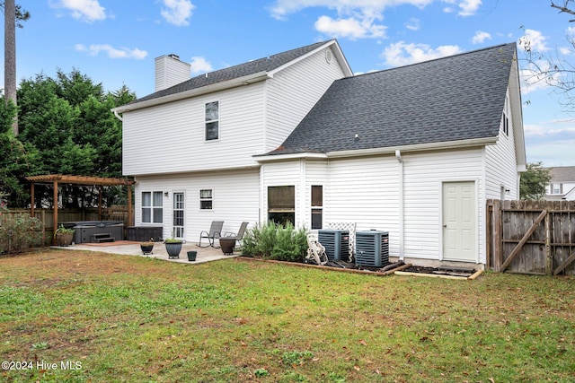 back of property featuring a yard, a hot tub, a patio area, and central air condition unit