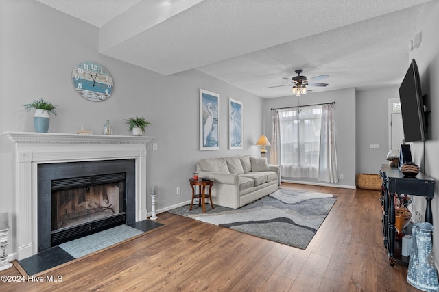 living room with ceiling fan, dark hardwood / wood-style flooring, and a textured ceiling