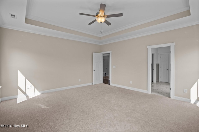 empty room with ceiling fan, light colored carpet, crown molding, and a tray ceiling