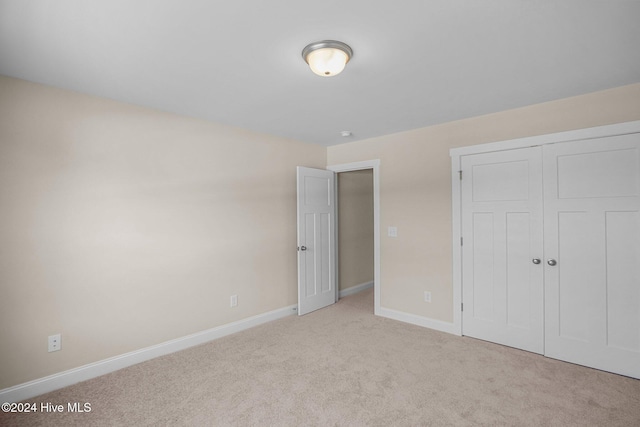 unfurnished bedroom featuring light carpet and a closet