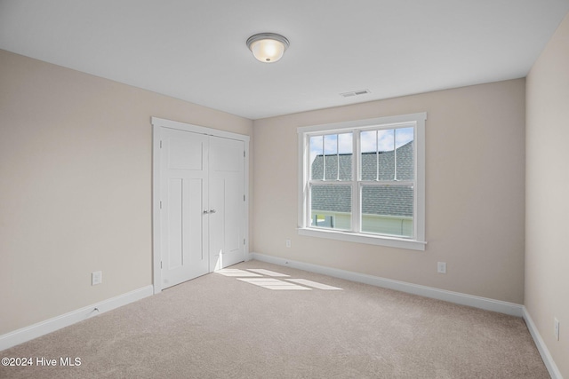 unfurnished bedroom with light carpet and a closet