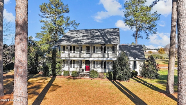 view of front facade with covered porch, a balcony, and a front lawn