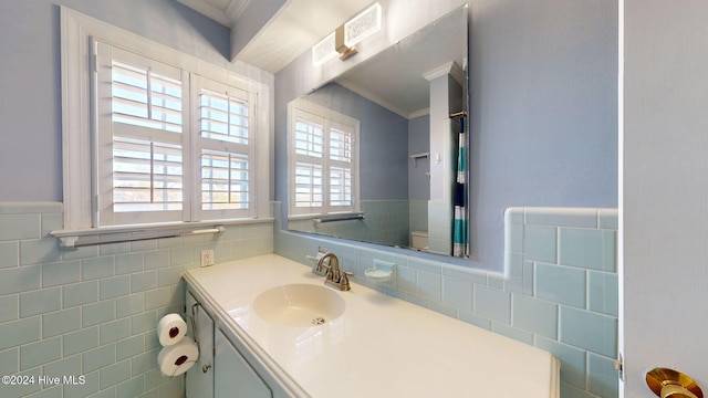 bathroom with plenty of natural light, ornamental molding, tile walls, and vanity