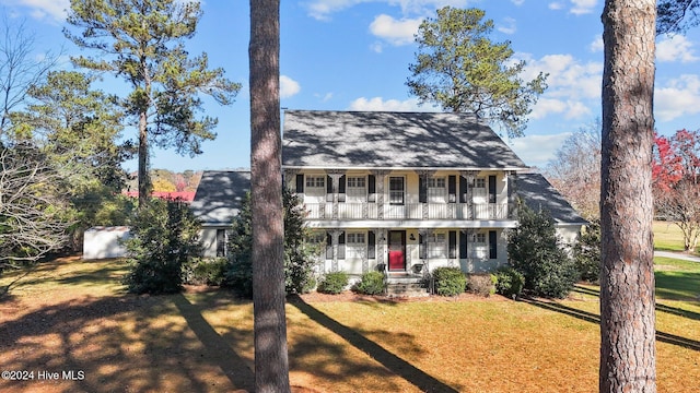 colonial home with a porch, a balcony, and a front yard