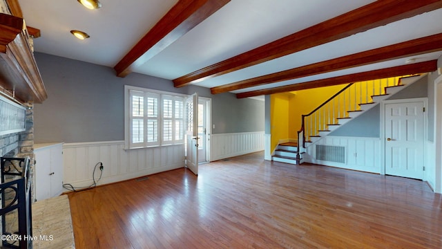 unfurnished living room featuring beamed ceiling, wood-type flooring, and a fireplace