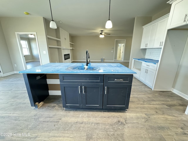 kitchen featuring hanging light fixtures, white cabinetry, sink, and a kitchen island with sink