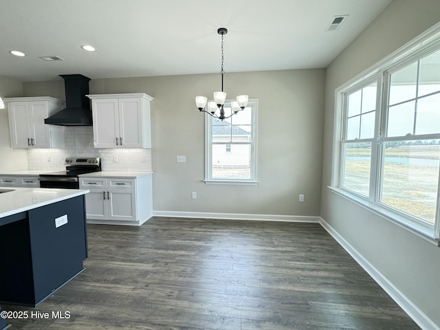 kitchen with baseboards, backsplash, electric stove, and wall chimney range hood