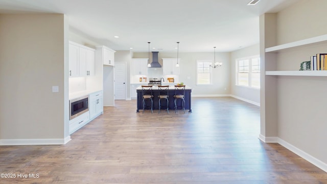 1407 Stoney Creek Church Rd, Goldsboro, NC 27534 - kitchen with wall chimney exhaust hood, a chandelier, stainless steel appliances, wood finished floors, and white cabinets