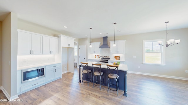 1407 Stoney Creek Church Rd, Goldsboro, NC 27534 - kitchen with wall chimney range hood, stainless steel appliances, backsplash, light wood-type flooring, and a kitchen breakfast bar