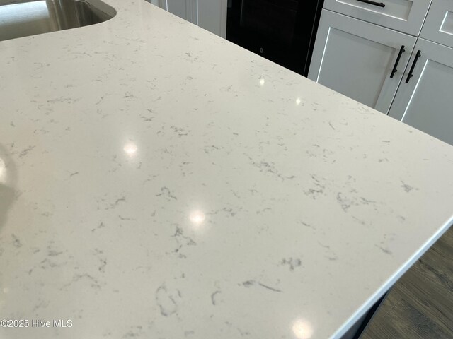 room details featuring a sink, light stone counters, and white cabinets