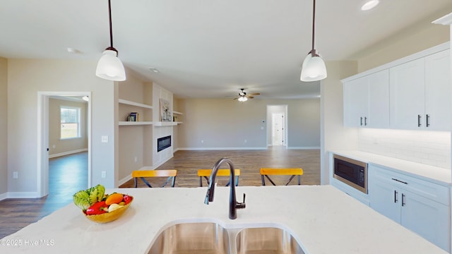 1407 Stoney Creek Church Rd, Goldsboro, NC 27534 - kitchen featuring a sink, wood finished floors, a glass covered fireplace, built in microwave, and pendant lighting