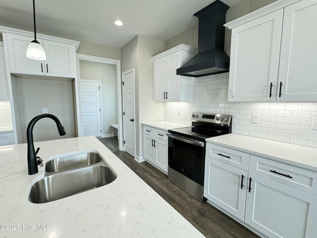 kitchen featuring a sink, wall chimney range hood, stainless steel electric range oven, white cabinetry, and dark wood-style flooring