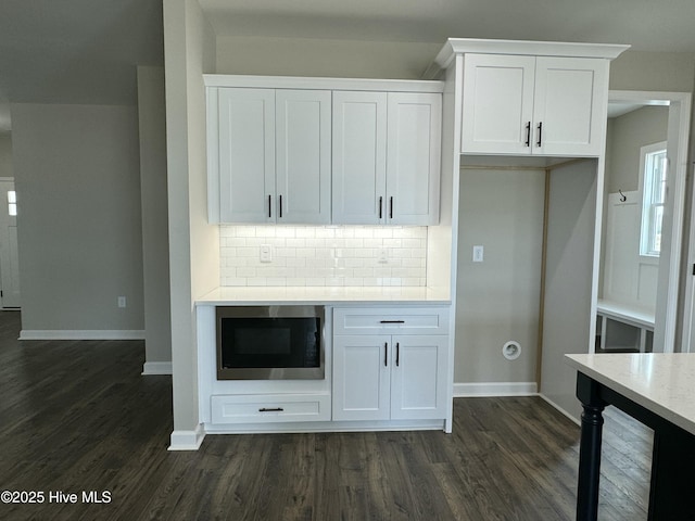 kitchen featuring built in microwave, white cabinets, backsplash, and dark wood-style flooring