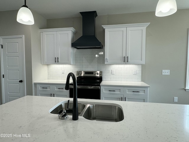 kitchen with backsplash, wall chimney range hood, light stone countertops, electric stove, and a sink