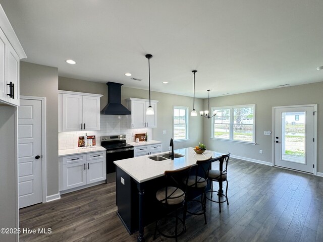 kitchen featuring hanging light fixtures, white cabinetry, sink, and a center island with sink