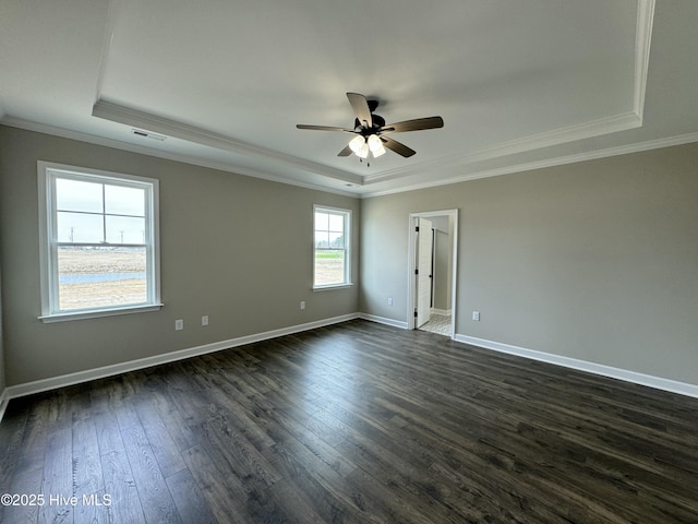 spare room with a raised ceiling, baseboards, dark wood-style flooring, and ornamental molding