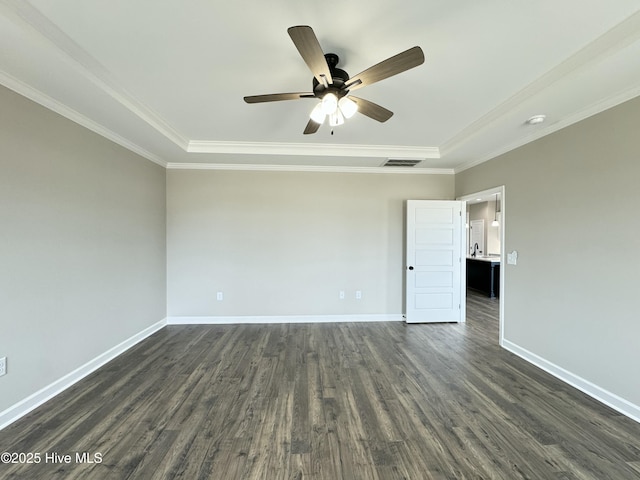 spare room featuring visible vents, crown molding, baseboards, dark wood finished floors, and a tray ceiling