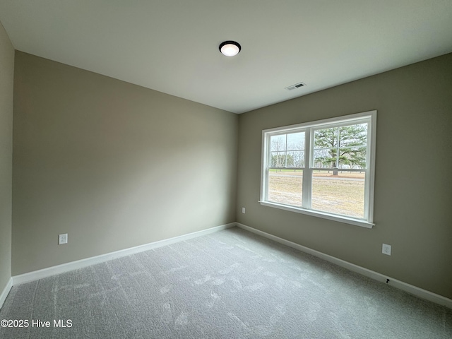 carpeted spare room with visible vents and baseboards