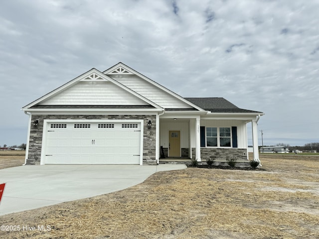 view of front of home featuring a garage, stone siding, and driveway