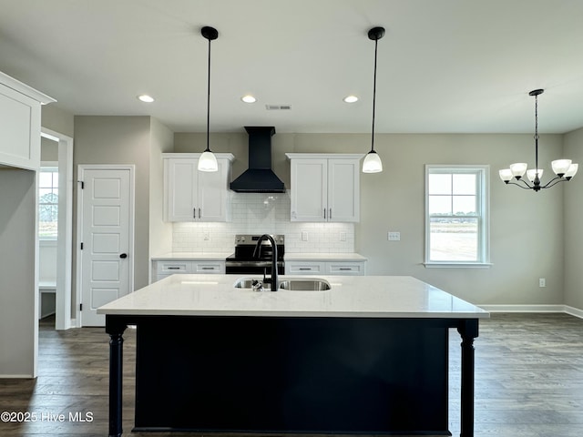 kitchen featuring decorative backsplash, wall chimney exhaust hood, visible vents, and a sink