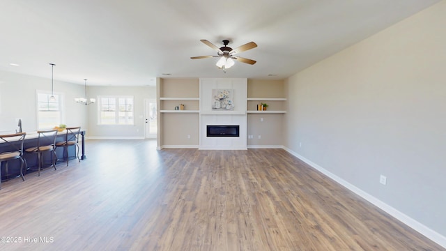 1407 Stoney Creek Church Rd, Goldsboro, NC 27534 - living room featuring wood finished floors, a ceiling fan, baseboards, a chandelier, and a tiled fireplace