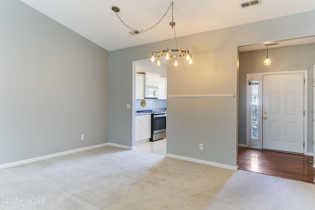 foyer featuring light carpet and an inviting chandelier