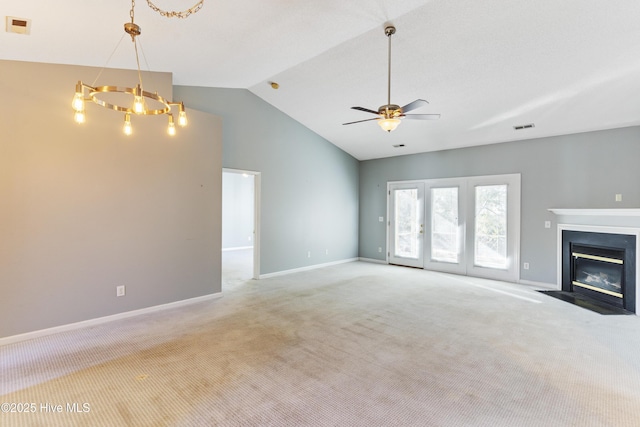 unfurnished living room with light carpet, ceiling fan with notable chandelier, and lofted ceiling