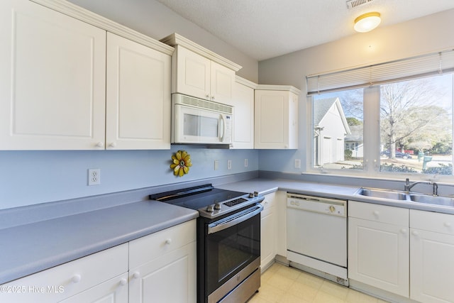 kitchen with a textured ceiling, white appliances, white cabinetry, and sink