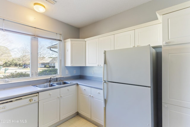 kitchen featuring white cabinets, white appliances, sink, and a textured ceiling