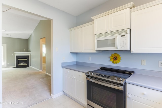 kitchen with electric range, light colored carpet, and white cabinetry