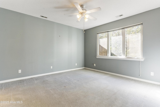 empty room with ceiling fan, light colored carpet, and a textured ceiling